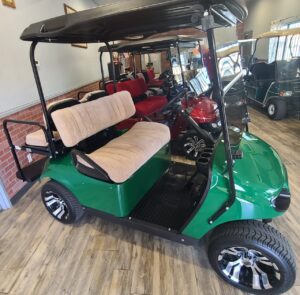 A green golf cart with people in the back.