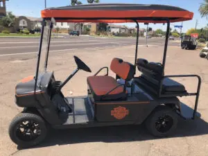 A golf cart with an orange and black design.