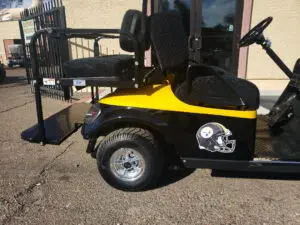 A yellow and black golf cart parked in front of a building.