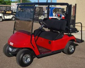 A red golf cart with black seats parked in the street.