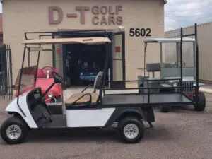 A golf cart is parked in front of the d-t golf cars.