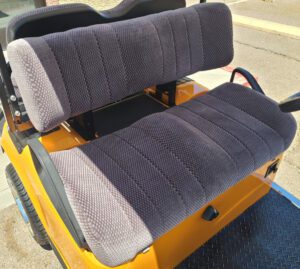 A yellow golf cart with two seats and a seat belt.