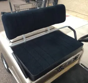 A golf cart seat with black fabric on it.
