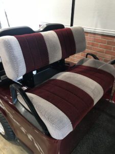 A car seat with two seats and one is covered in red, white and grey stripes.