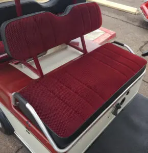 A red seat on top of a golf cart.