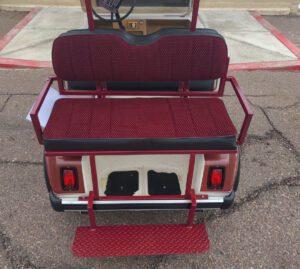 A red and white golf cart with two seats.